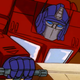 A hunched-over Optimus Prime frantically tries to work his spaceship's controls.